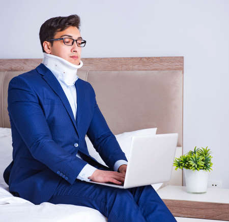Businessman with neck injury working from homeの写真素材