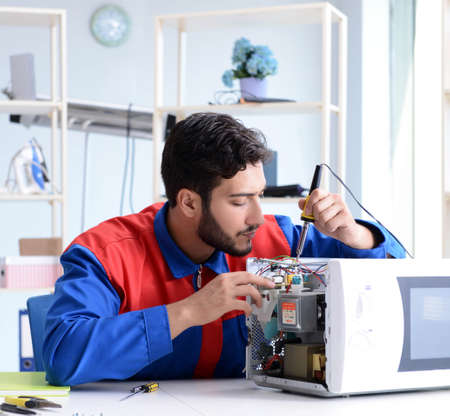 Young repairman fixing and repairing microwave ovenの写真素材