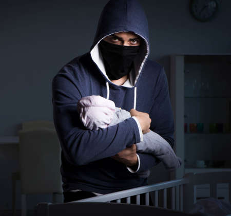 Criminal stealing baby in human child traficking conceptの写真素材