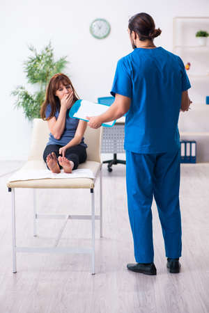 Finger injured woman visiting male doctor traumatologistの写真素材