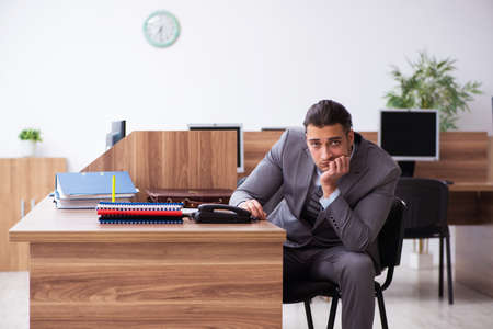 Young male employee unhappy with excessive workの写真素材