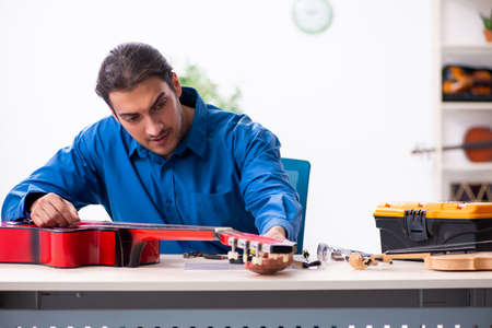 Young male repairman repairing guitar
