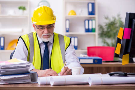 Old male architect working in the office