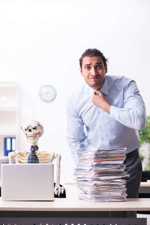 Young male employee and skeleton in the officeの写真素材