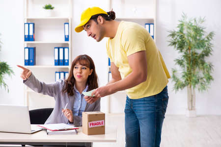 Young male courier delivering parcel to the officeの写真素材