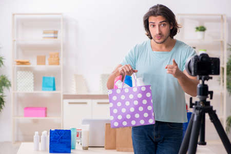 Young male shopaholic recording video for his blogの写真素材