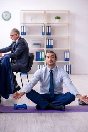Two employees doing physical exercises at workplaceの写真素材