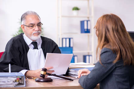 Old male judge and female client in the office