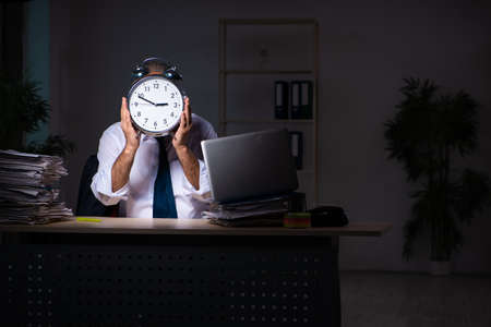 Old male employee working late at workplaceの写真素材