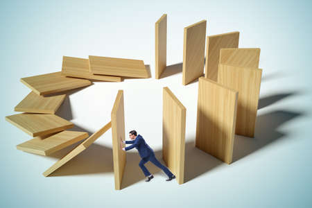 Businessman in domino effect conceptの写真素材