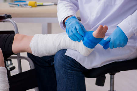 Young injured woman visiting old doctor traumatologist