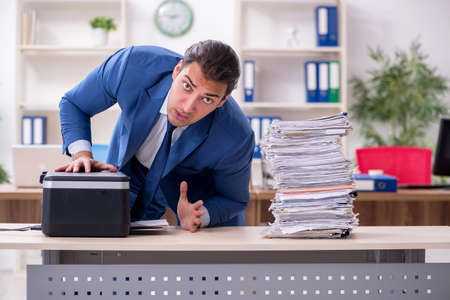 Young male employee making copies at copying machineの写真素材