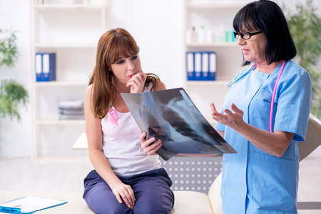 Young woman visiting old doctor oncologist in breast cancer