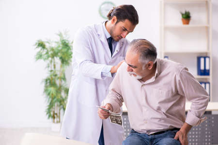 Old patient visiting young male doctorの写真素材