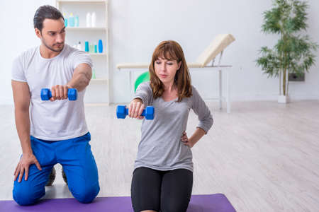 Young woman doing sport exercises with personal coachの写真素材