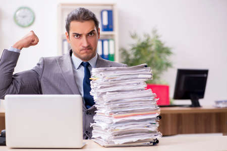 Young male businessman unhappy with excessive workの写真素材