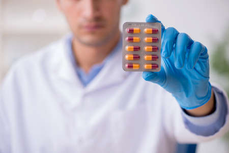 Young male lab assistant in drug synthesis conceptの写真素材