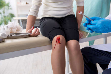 Leg injured woman visiting male doctorの写真素材