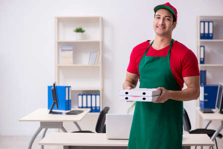 Young male courier delivering pizza to the officeの写真素材