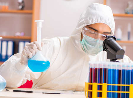 Young biochemist wearing protective suit working in the lab