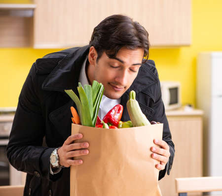 Young handsome man with vegetables in kitchenの写真素材