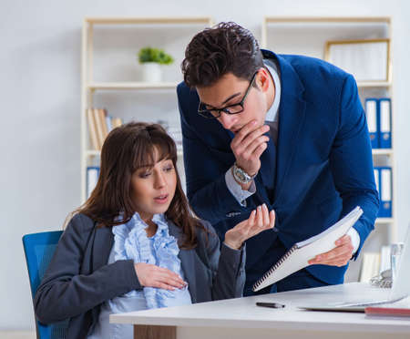 Pregnant woman struggling in the office and getting colleague heの写真素材