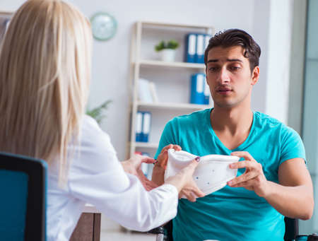 Disabled man in wheel chair visiting woman doctorの写真素材