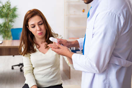 Young hand injured woman visiting male doctor traumatologistの写真素材