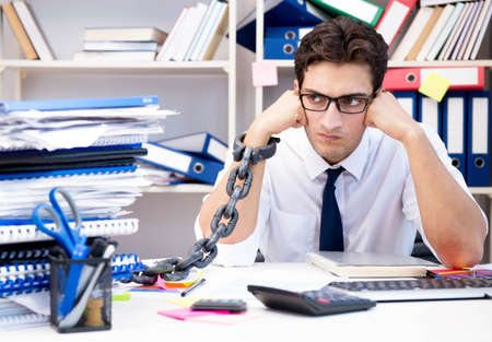 Employee attached and chained to his desk with chainの写真素材