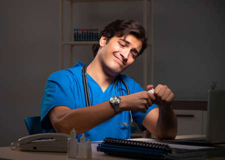 Young handsome doctor working night shift in hospitalの写真素材