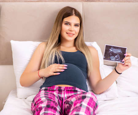 Happy young pregnant woman in the bedの写真素材