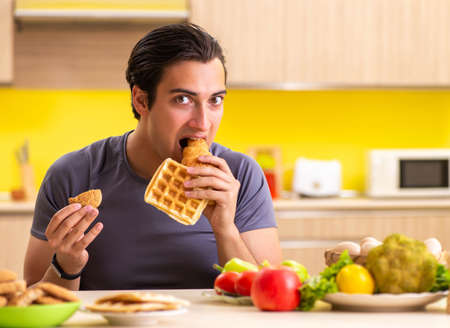 Man having hard choice between healthy and unhealthy foodの写真素材