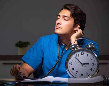 Young handsome doctor working night shift in hospitalの写真素材