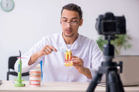 Young male doctor dentist recording video for his blogの写真素材