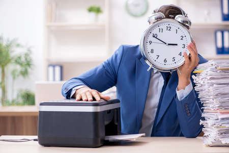 Young male employee making copies at copying machine