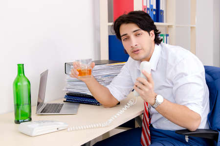 Young businessman employee drinking in the officeの写真素材