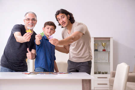 Three generations of family playing jigsaw puzzle gameの写真素材