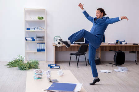 Young male employee playing football in the officeの写真素材