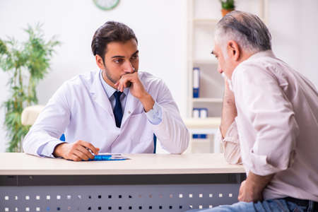 Old patient visiting young male doctorの写真素材