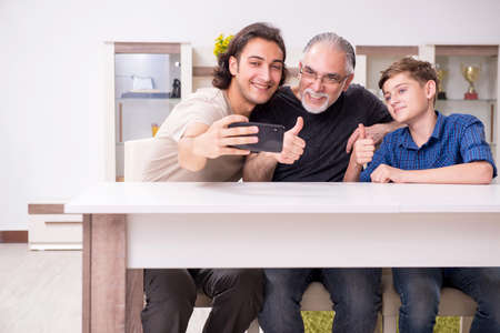 Grandfather learning new technology from son and grandsonの写真素材