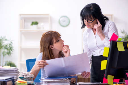 Two female employees and excessive work in the officeの写真素材