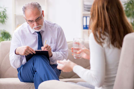 Young woman visiting old male doctor psychologistの写真素材