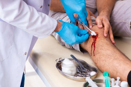 Leg injured man visiting doctor in first aid conceptの写真素材