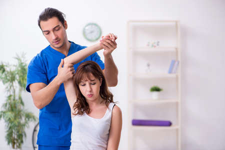 Injured woman visiting young male doctor osteopath