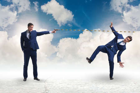 Businessman with gun threatening his competitorの写真素材