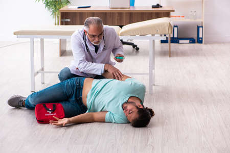 Experienced doctor and young male patient in first aid concept