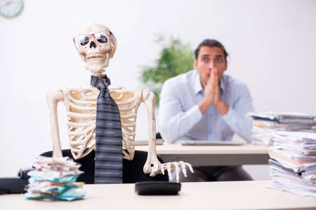 Young male employee and skeleton in the officeの写真素材