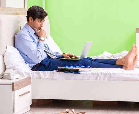 Businessman working overtime in hotel roomの写真素材