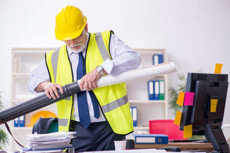 Old male architect working in office
