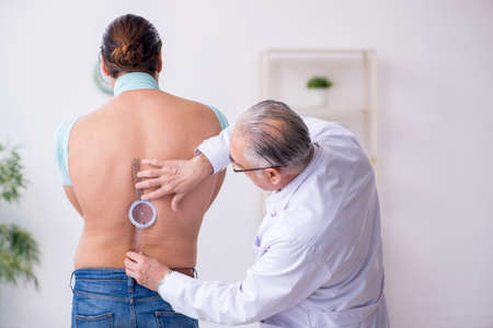 Young back injured man visiting experienced doctorの写真素材